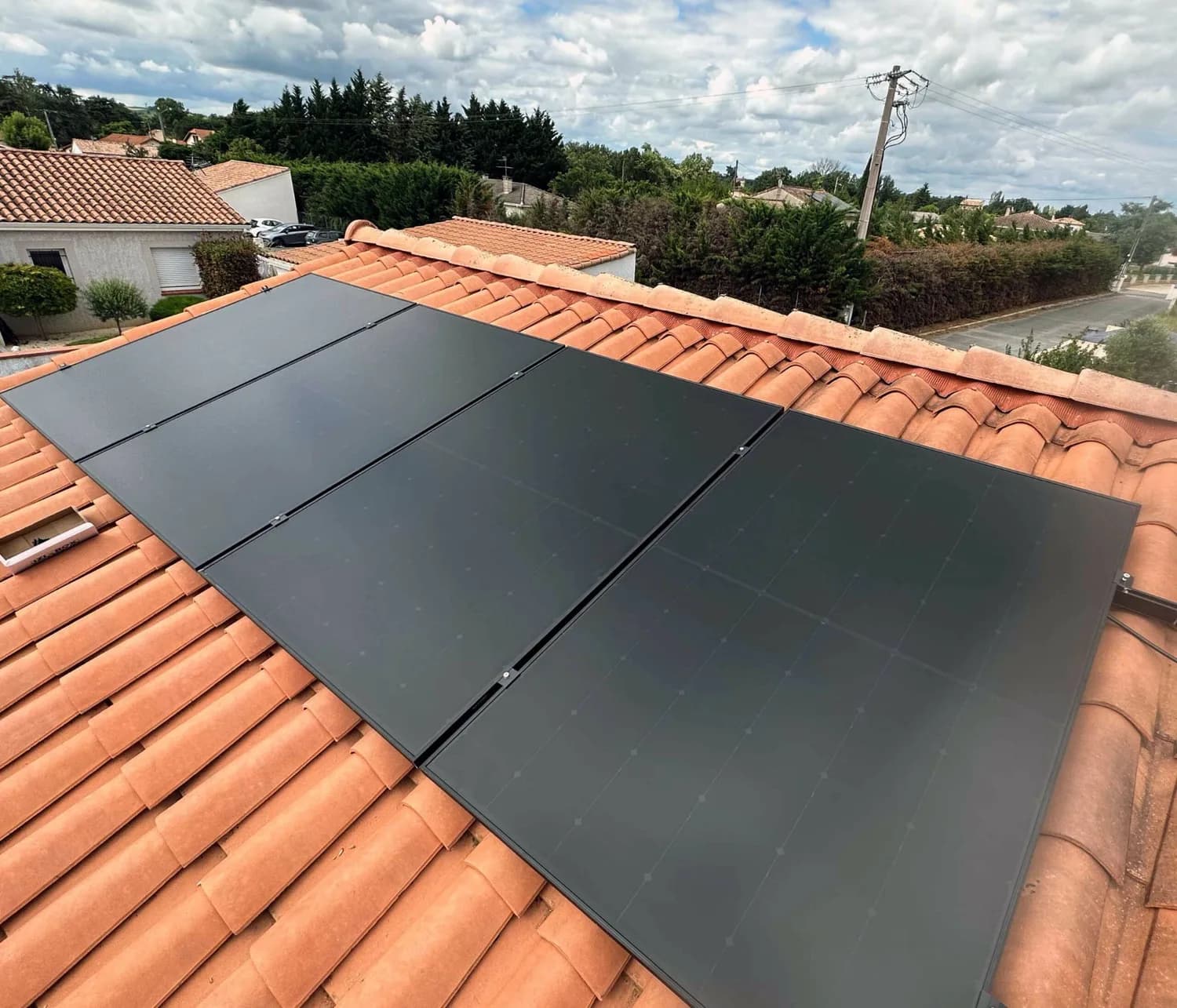 Rangée de panneaux solaires noirs sur un toit en tuiles